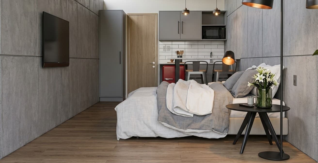 Interior de CRUDO 02: dormitorio con muros de hormigón visto y kitchenette al fondo