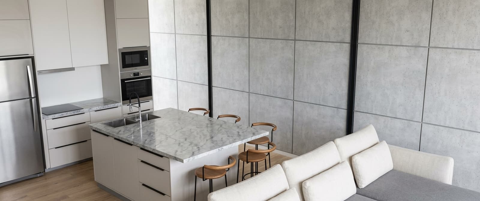 Cocina y estar integrados de CRUDO 03, con isla de mármol y muro de hormigón visto
