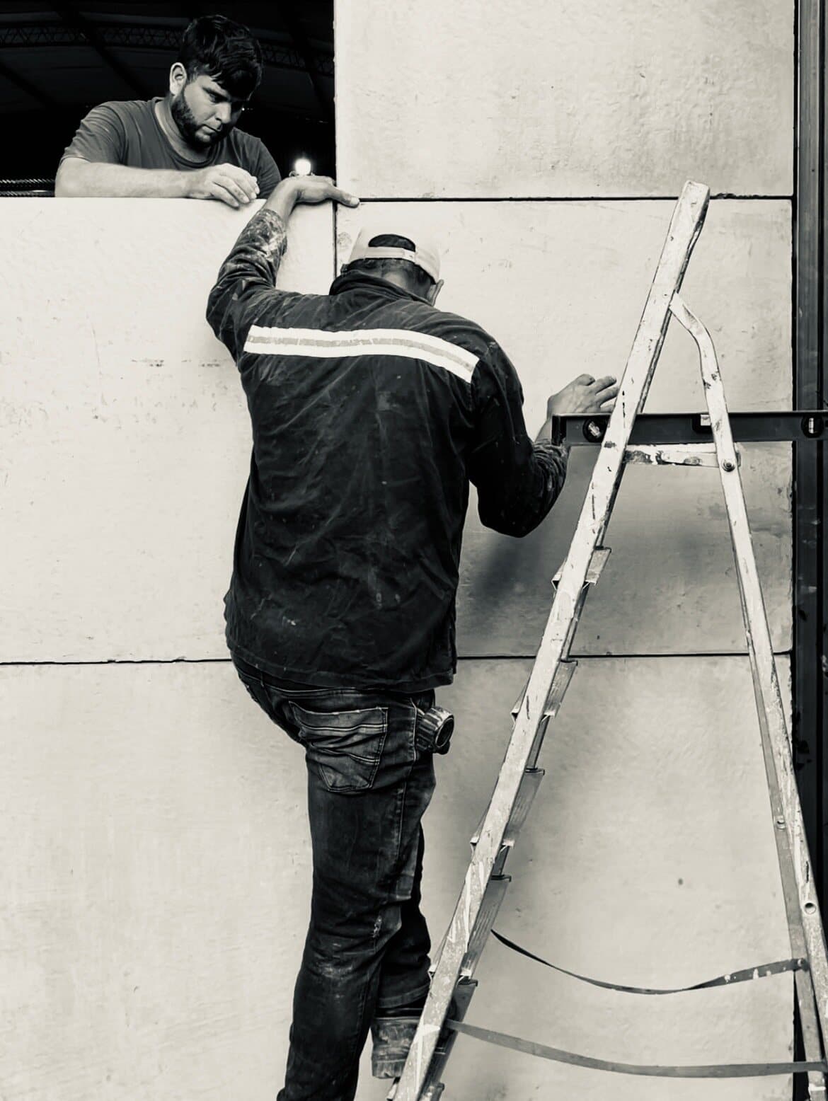 Dos operarios nivelando placas de hormigón durante el montaje de un muro