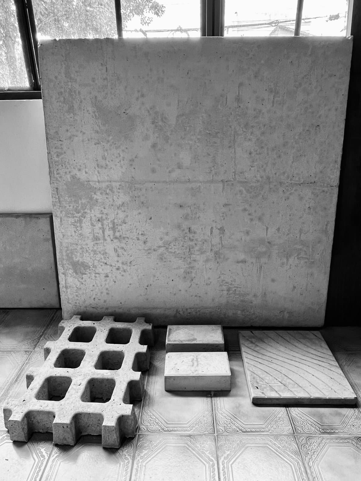 Placa de hormigón visto junto a un bloque calado, ladrillos y una baldosa de concreto